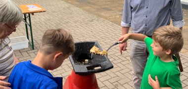 A boy puts pieces of apple into a chopper