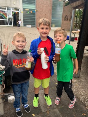 Three boys show their pressed apple juice