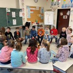 Children sit in a circle with a young woman