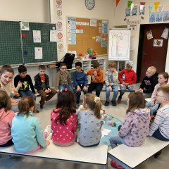 Children sit in a circle with a young woman