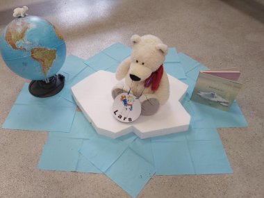 L'animal de la classe, l'ours polaire, est assis sur une banquise, avec un globe et un livre à côté de lui.
