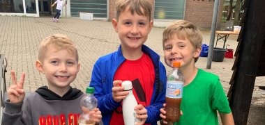 Tre ragazzi mostrano il loro succo di mela pressato