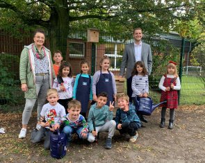 I bambini, l'insegnante e i rappresentanti di Volksbank Ahaus si trovano davanti al letto rialzato.