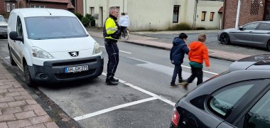 Due bambini attraversano la strada con un poliziotto