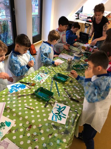 Kinderen in schilderpakjes schilderen met acrylverf